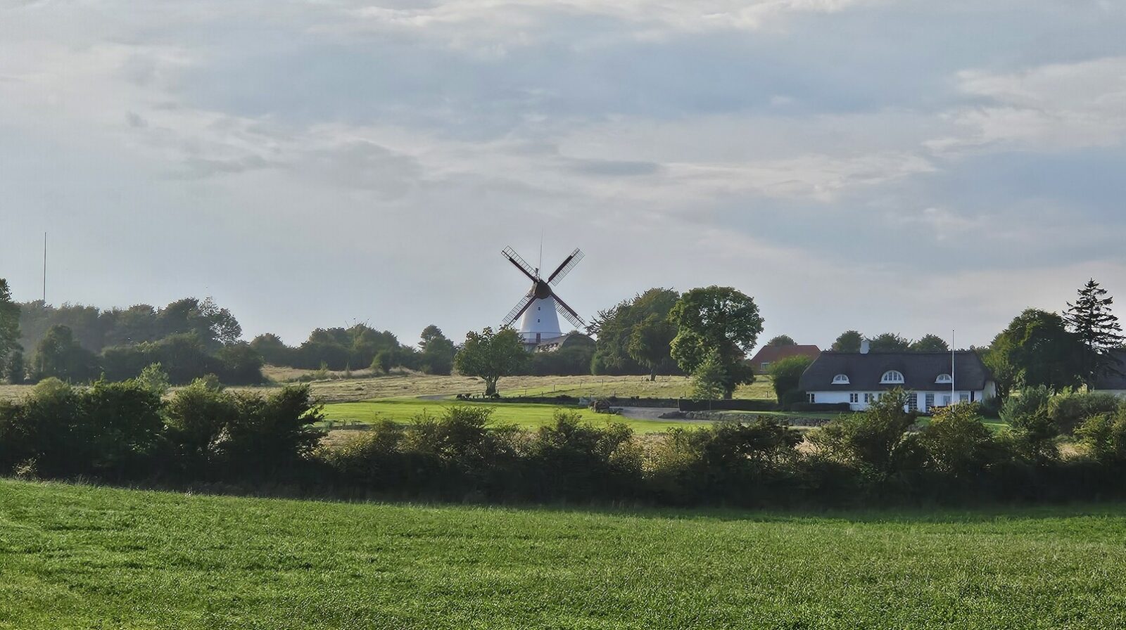 Foto af et sensommerlandskab og Dybbøl Mølle.