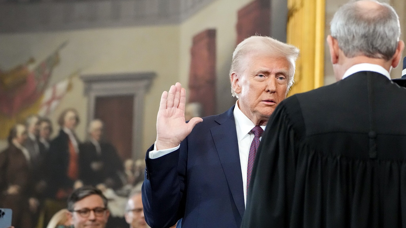 Foto af Trump, der hæver højre arm, da han aflægger ed ved sin indsættelse.