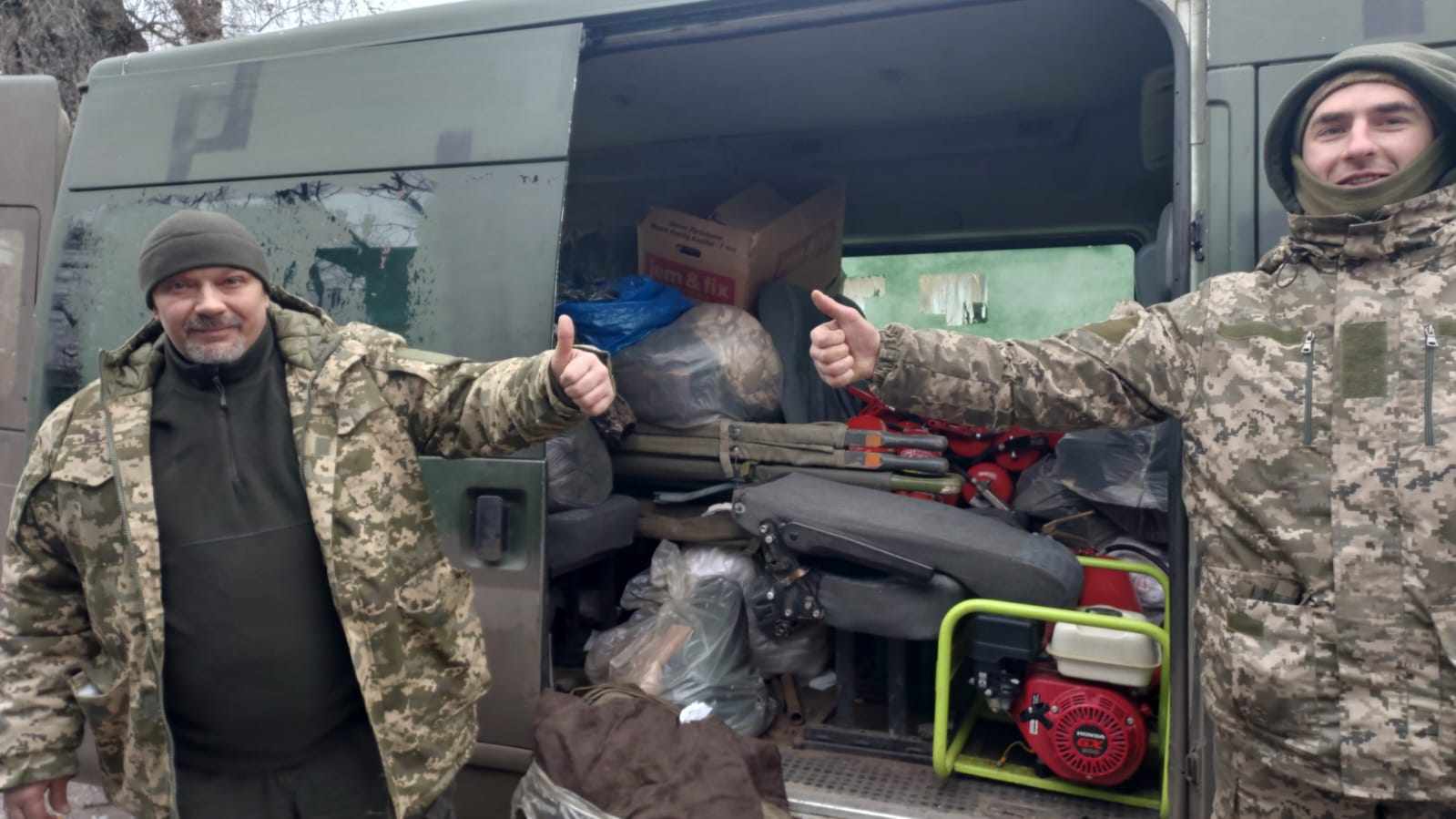 Soldater i ukraine iført uniform står foran grøn kassevogn. 