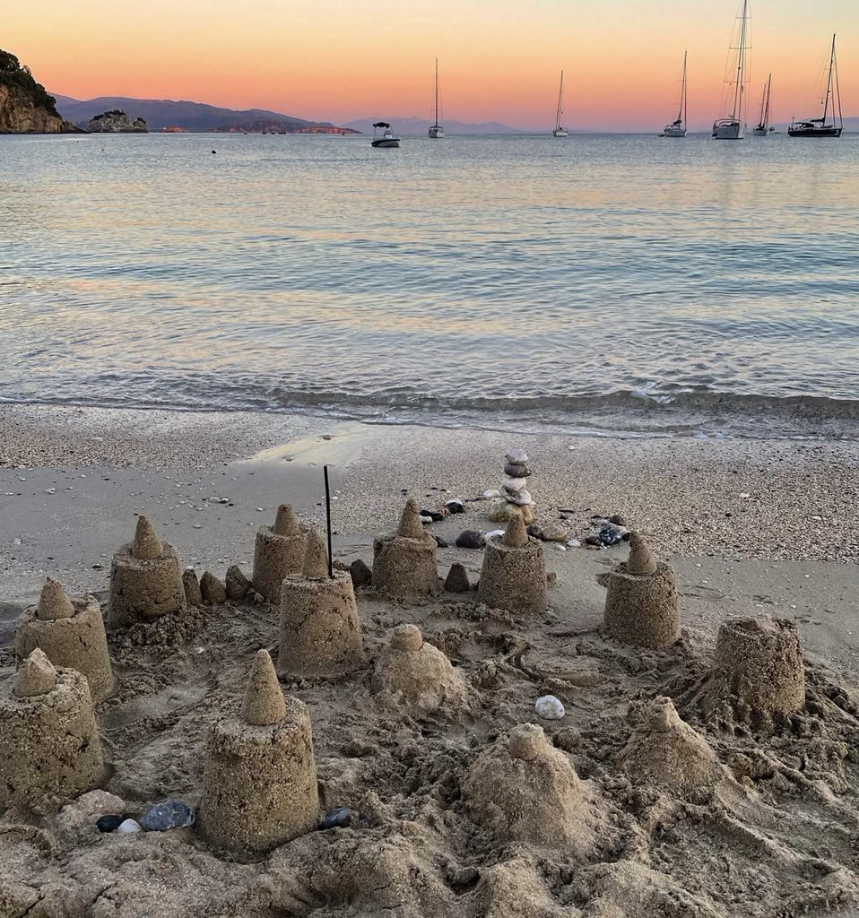 Græsk strand med både i baggrunden