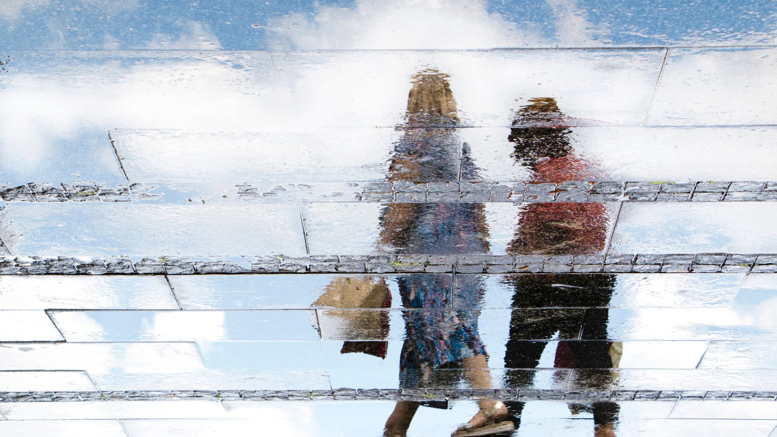 Et foto af to gående personer i skær af regn og sol - som illustration af en ny socialpolitisk orden for danskerne.