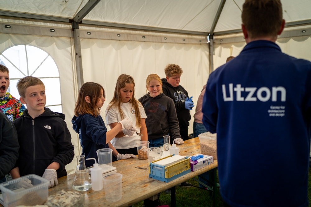 Piger og drenge deltager i et slags forsøg med bl.a. kolber i et telt.