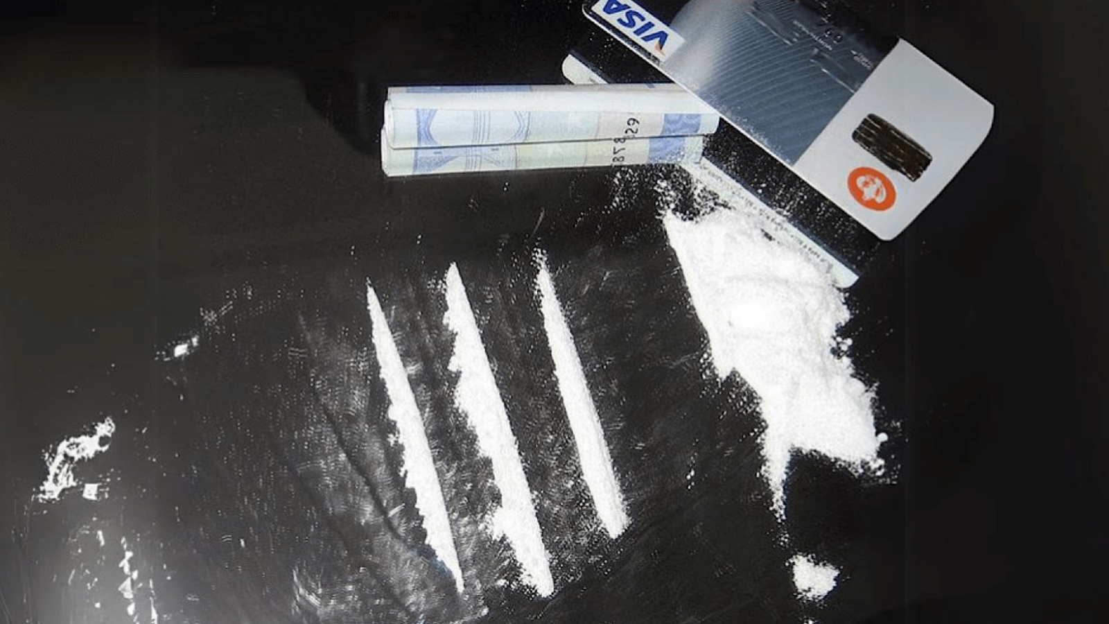 Baner af kokain og en rullet pengeseddel.