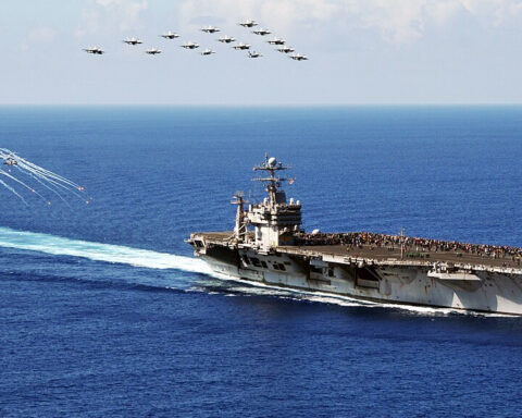 F/A-18 Hornets and Super Hornets from Carrier Air Wing (CVW) 2 fly in formation as MH-60S Seahawk helicopters assigned to the Golden Falcons of Helicopter Sea Combat Squadron (HSC) 12 fire flares during an air power demonstration above the Nimitz-class aircraft carrier USS Abraham Lincoln (CVN 72). Lincoln is returning to the United States after the completion of an eight-month change-of-homeport deployment during which it operated in the U.S. 5th, 6th and 7th Fleet areas of responsibility. (U.S. Navy photo by Mass Communication Specialist Seaman Zachary A. Anderson/Released